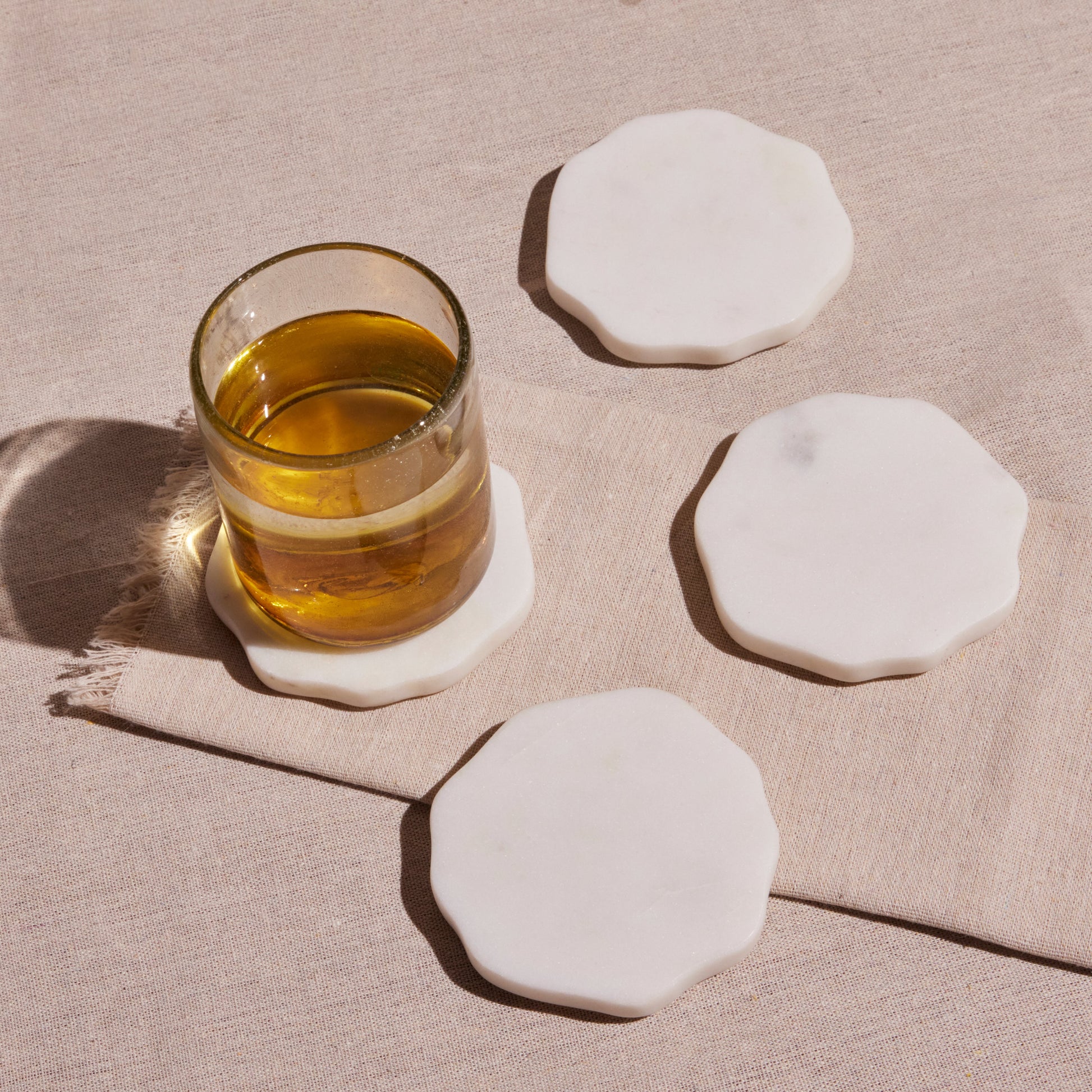 An amber beverage and Set of four white, handmade marble beverage coasters from Honduras.